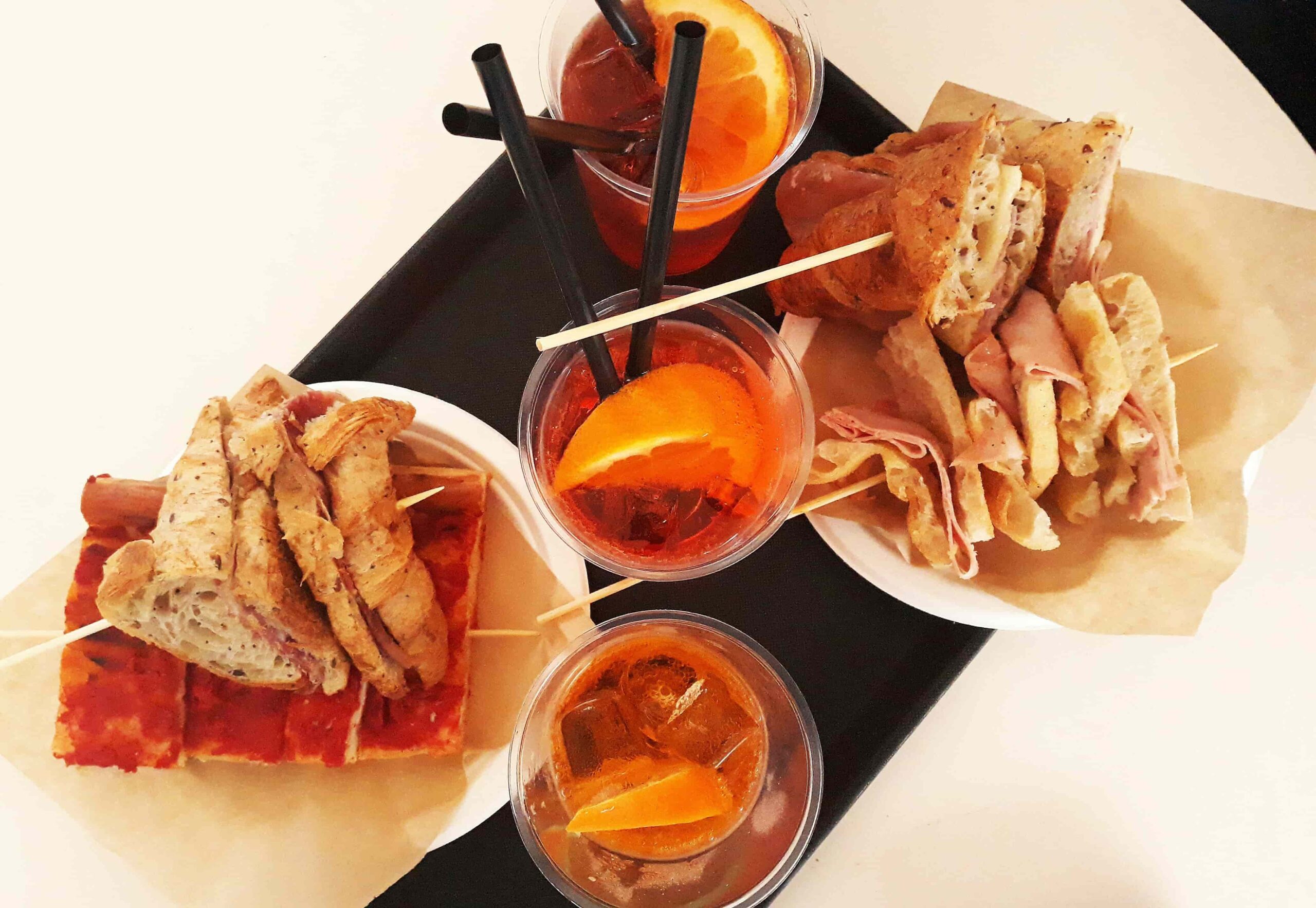 Eine gemütliche Abendszene in einer Bar in Bologna, mit Aperol Spritz, Weingläsern und einer Platte mit Wurstwaren, Käse und Oliven. Die warme Beleuchtung und entspannte Atmosphäre fängt die Tradition des italienischen Aperitivos ein.