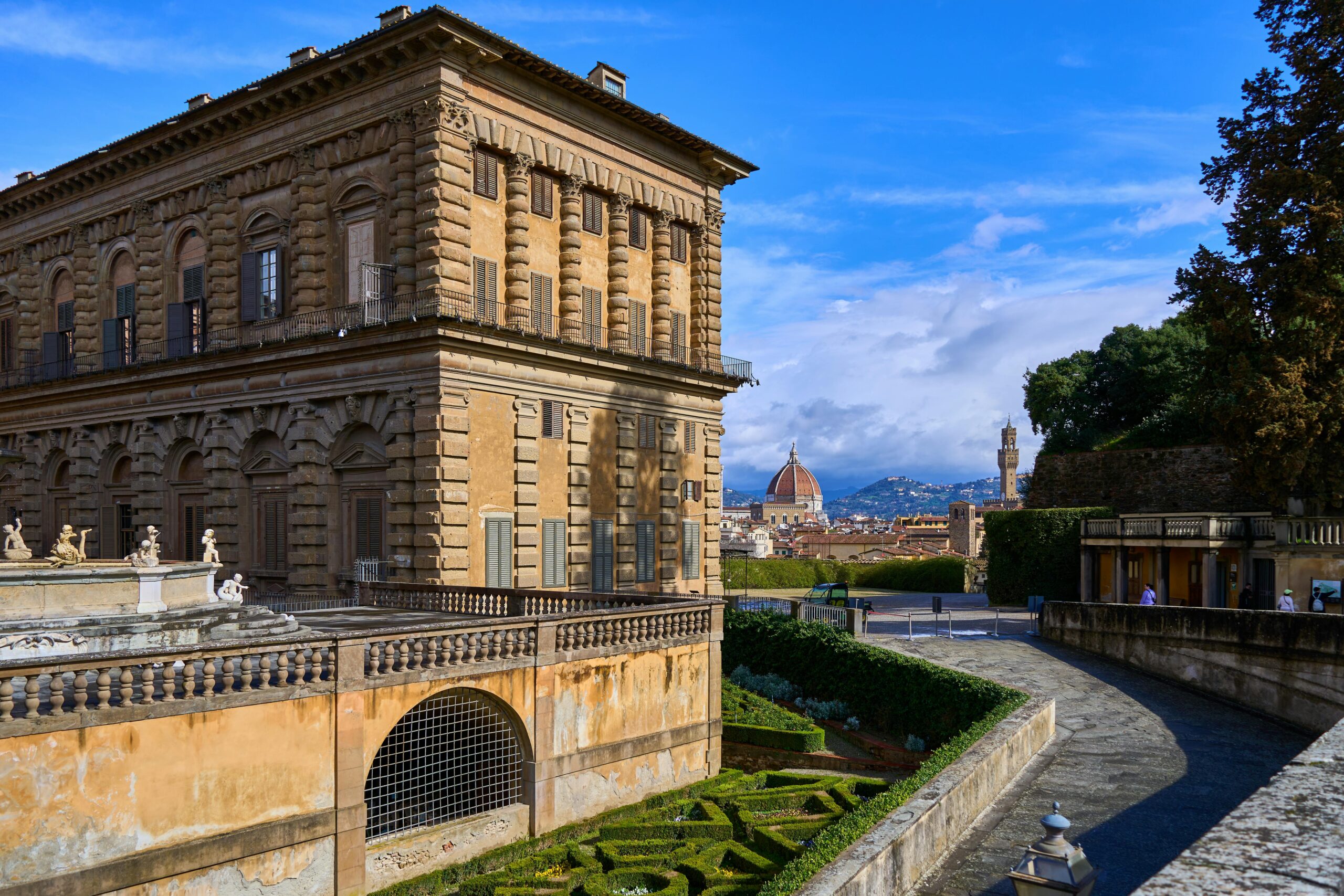 View of Palazzo Pitti and Florence Cathedral under a blue sky, showcasing Renaissance architecture.