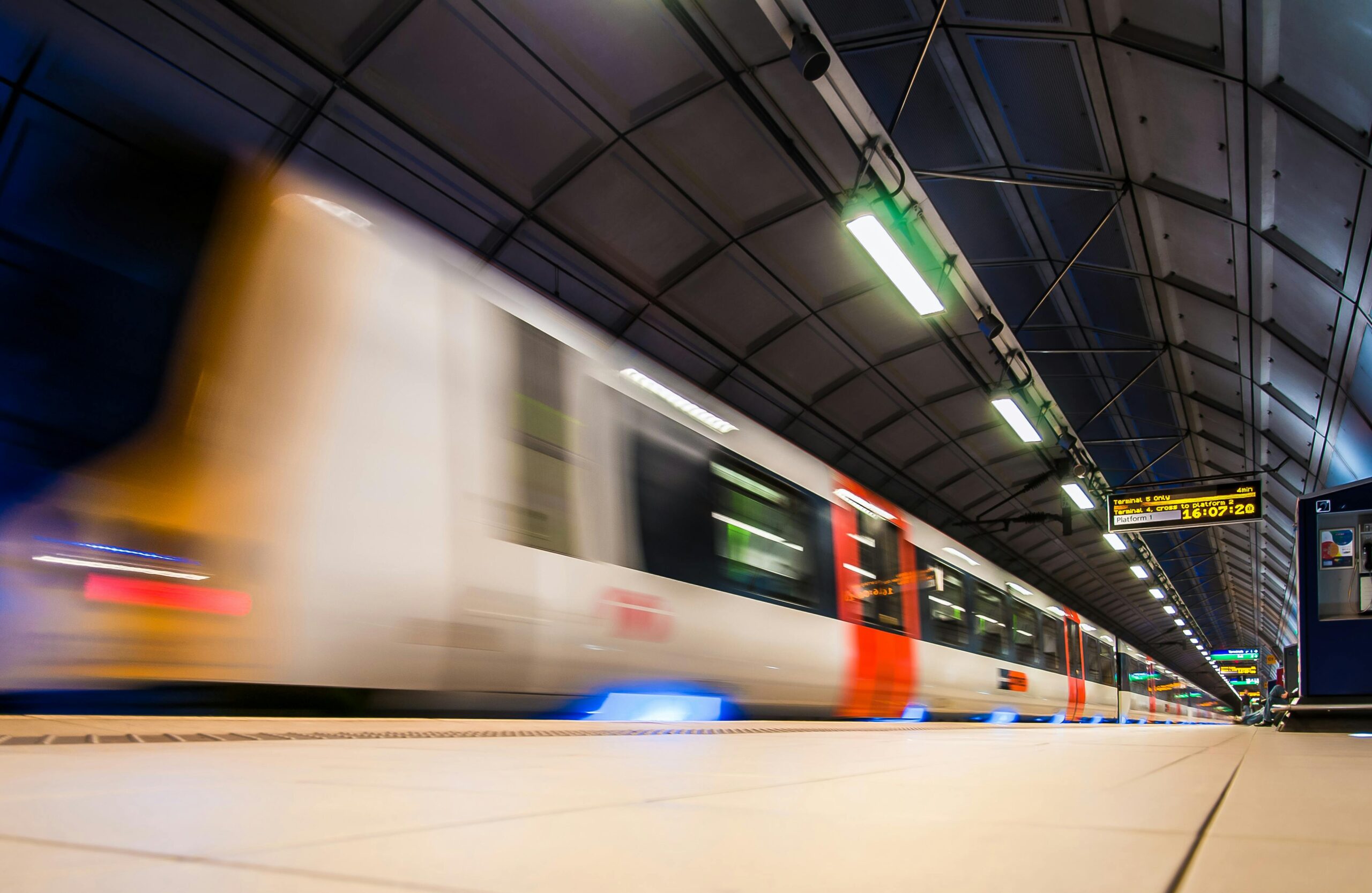 Train moving through a station beside a passenger platform