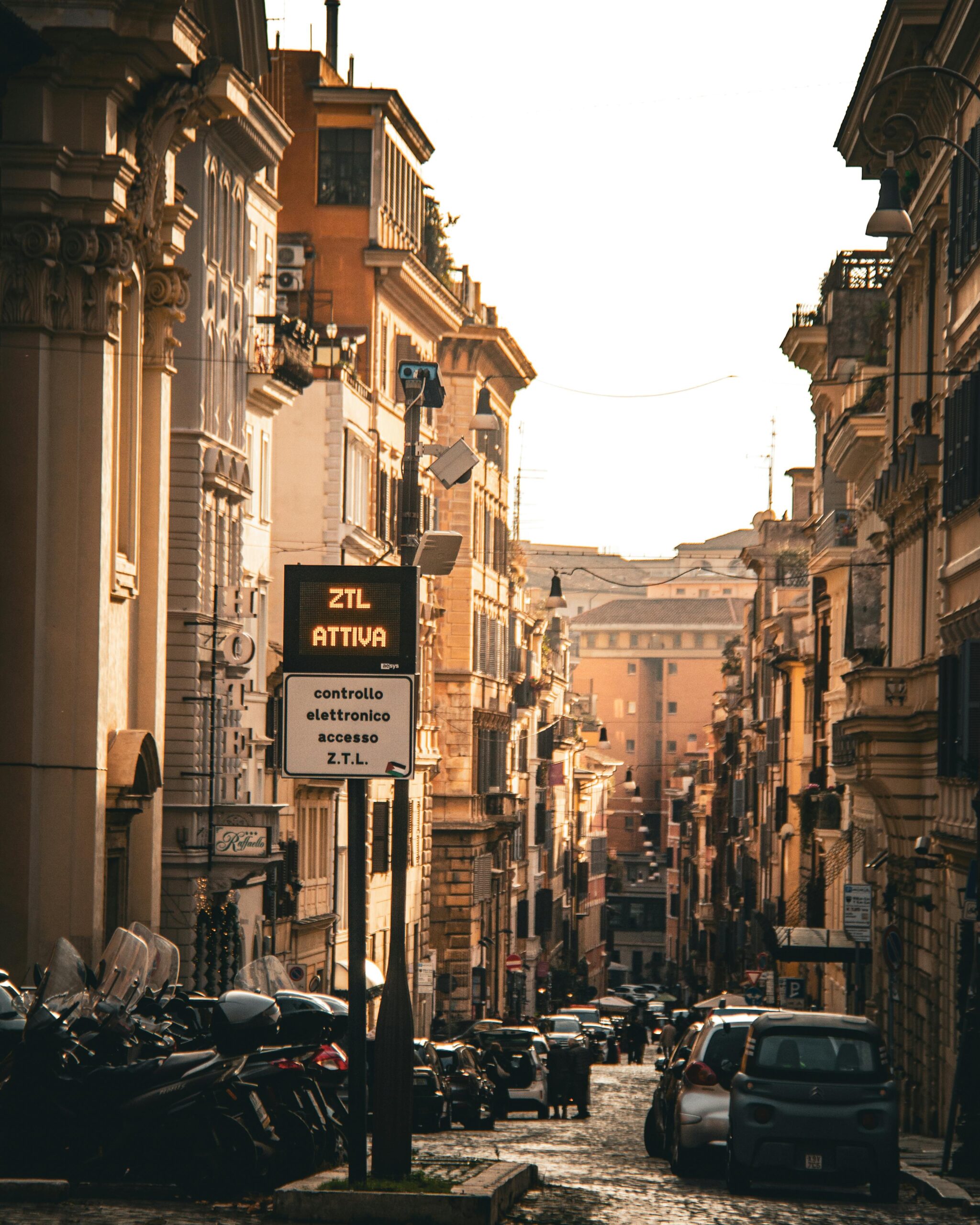 Italian street lined with parked cars and motor scooters