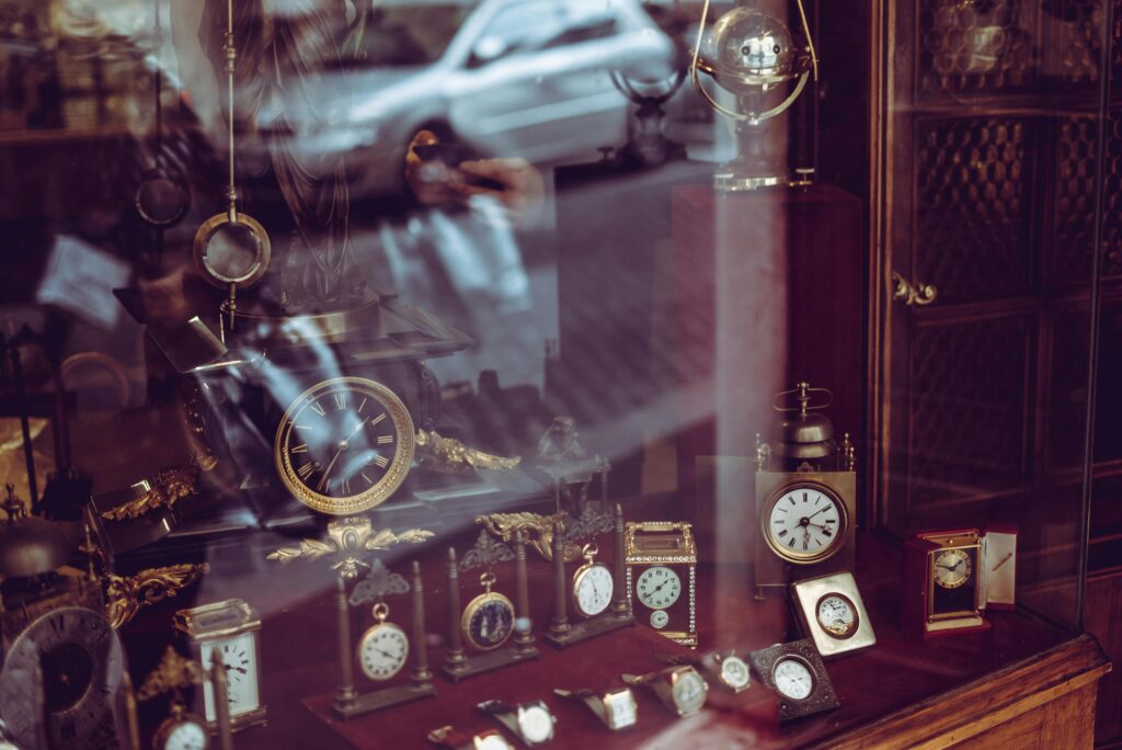 Vintage clock collection showcased in a Roman shop with reflective glass and elegant designs.