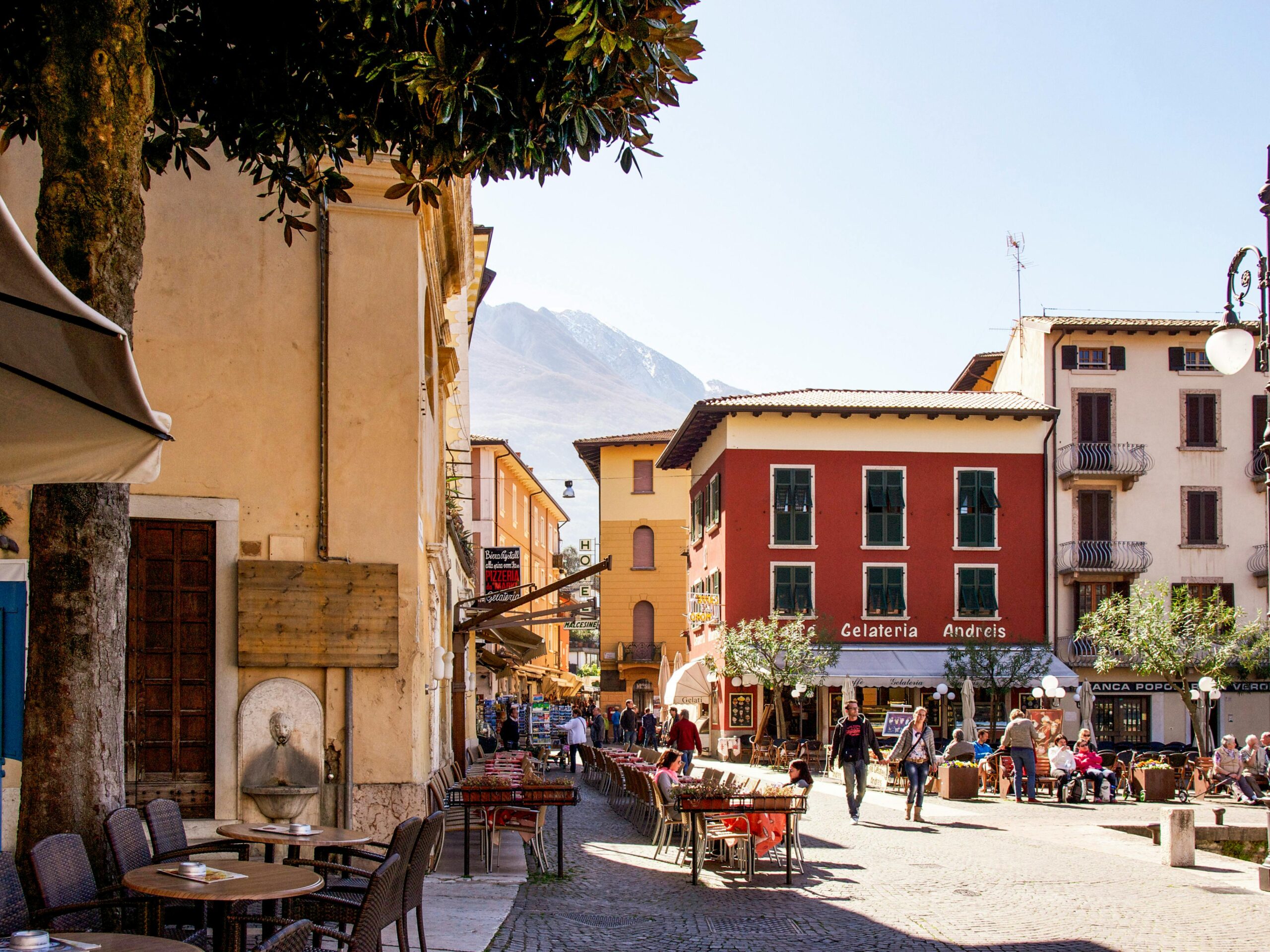 Picturesque Italian street with people at sunny outdoor cafes and shops