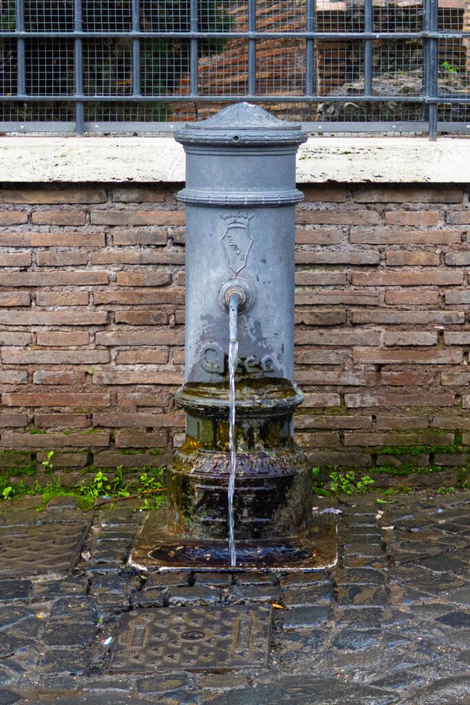 Classic iron water fountain, Nasone, in a scenic Rome setting, ideal for tourists.