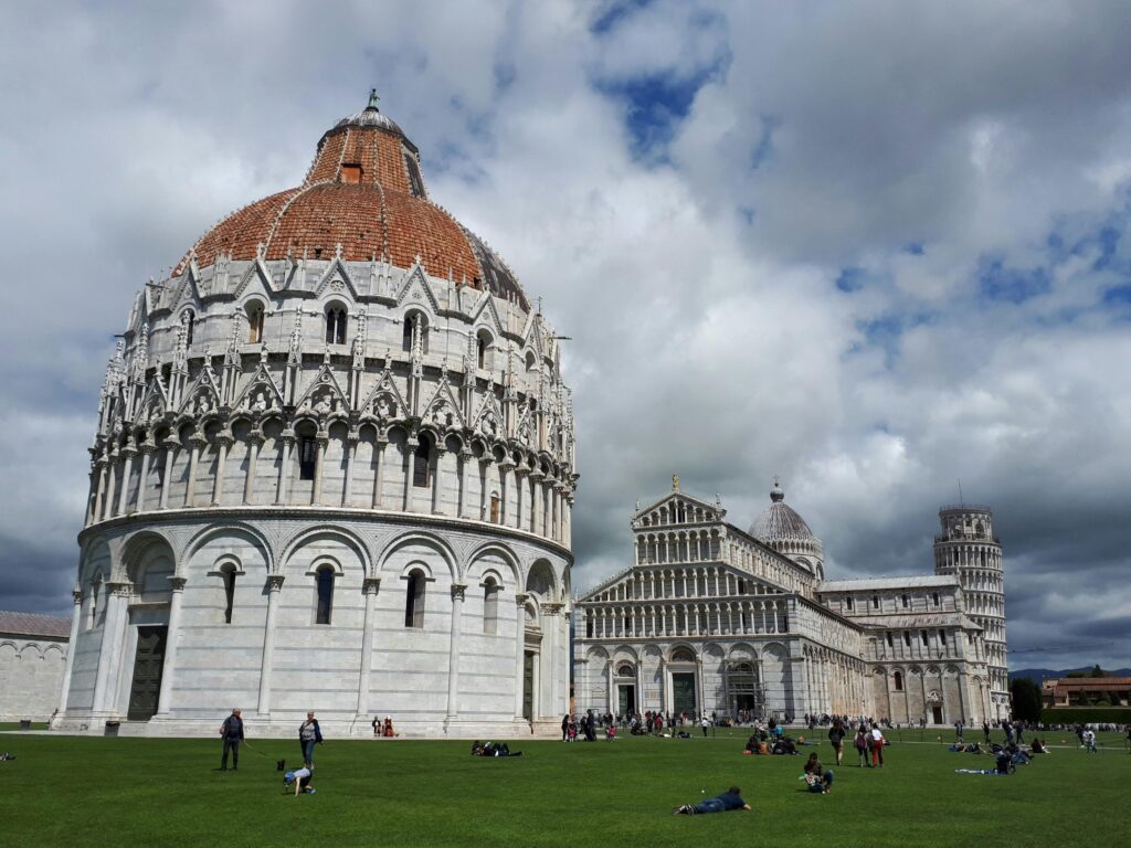 Explore the iconic Pisa Cathedral and Leaning Tower under a dramatic sky.