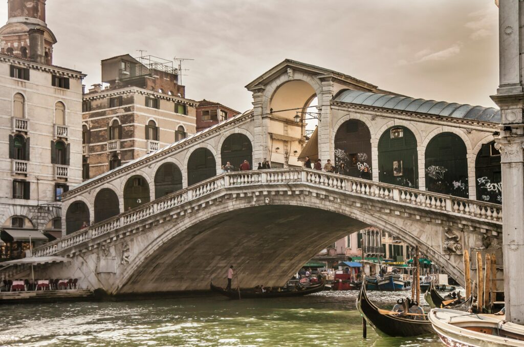 Scenic view of the historic Rialto Bridge and gondolas on the Grand Canal in Venice, Italy.