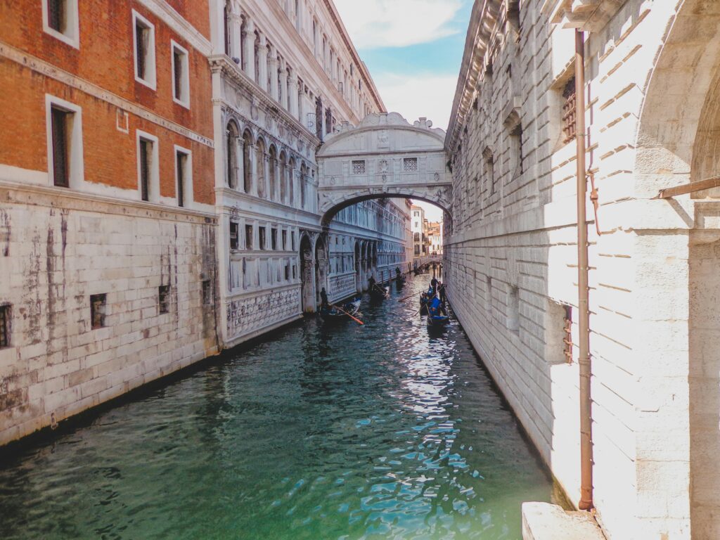 Iconic Bridge of Sighs spanning a tranquil canal in Venice, Italy, with gondolas passing underneath.