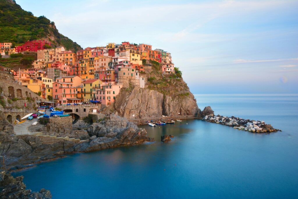 Scenic view of colorful houses and cliffs in Manarola, Liguria, Italy during summer.