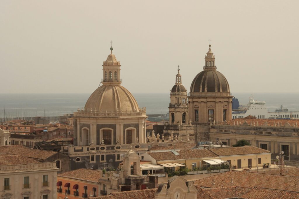 Impressive aerial shot of Catania Cathedral domes overlooking the sea in Sicily, Italy.