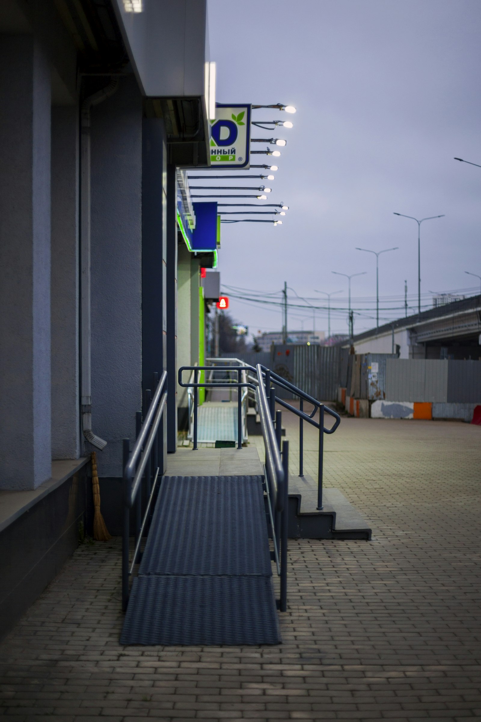 Accessible entrance ramp with handrails beside a set of steps