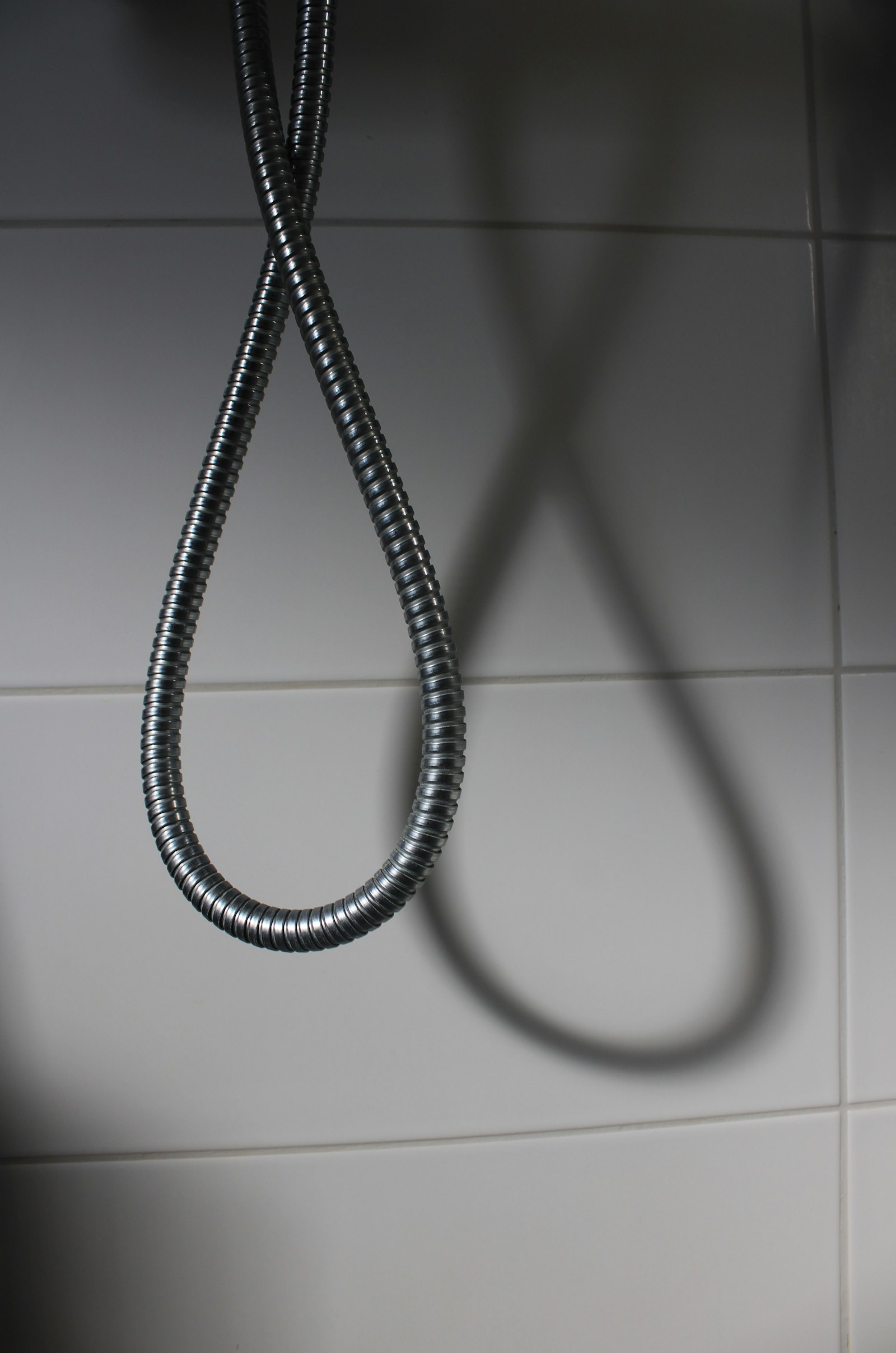 Pull cord hanging against white bathroom wall tiles