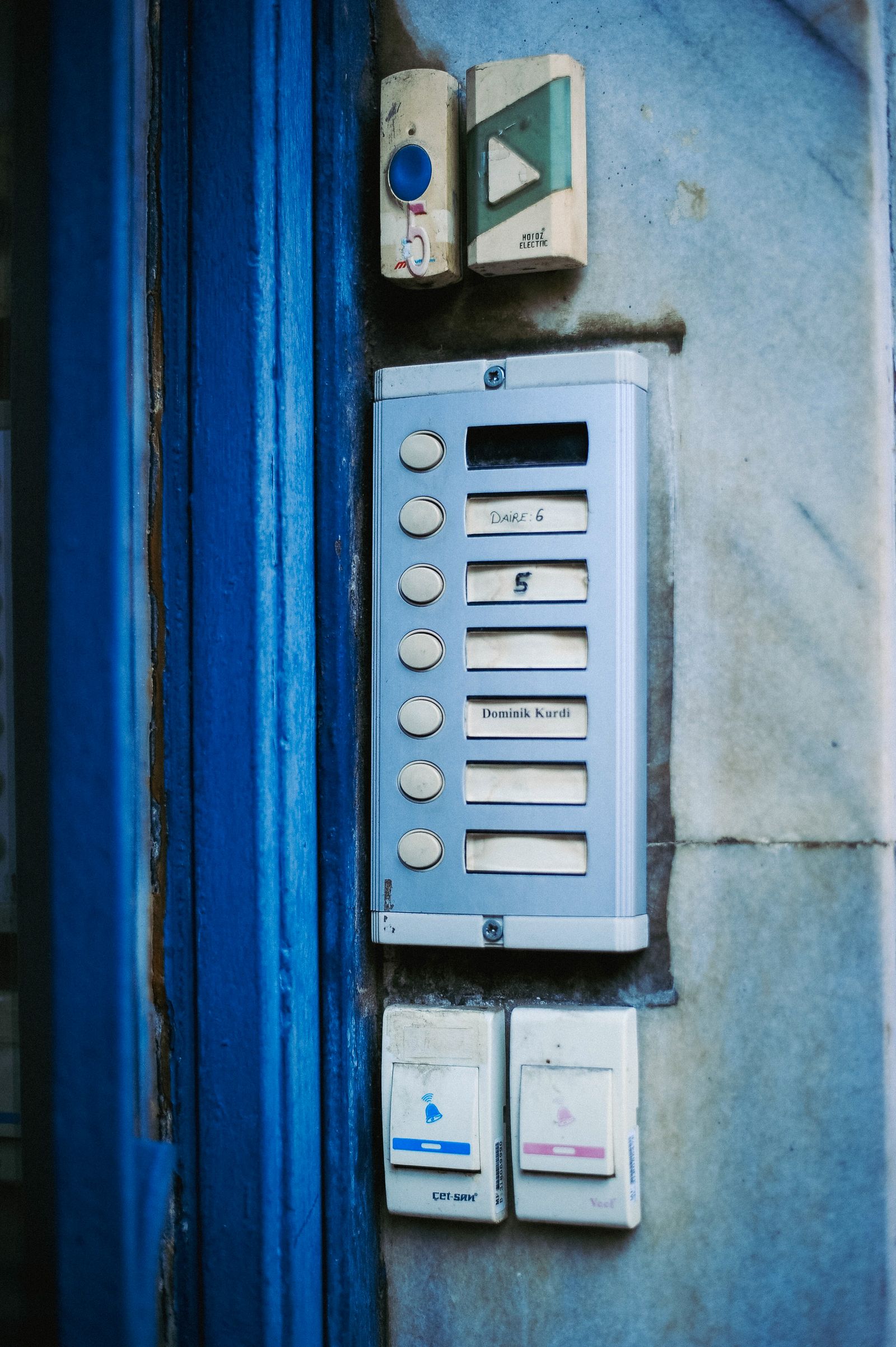 Close-up of a building intercom panel with multiple numbered buttons and name slots beside the entrance