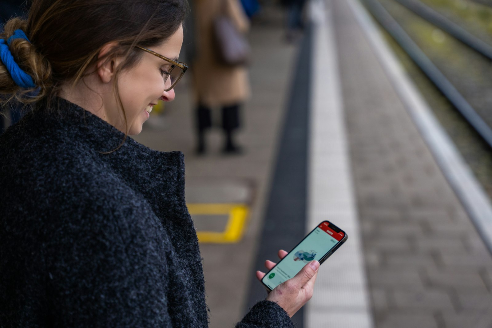 Traveller standing on a train platform checking a ticket on a phone