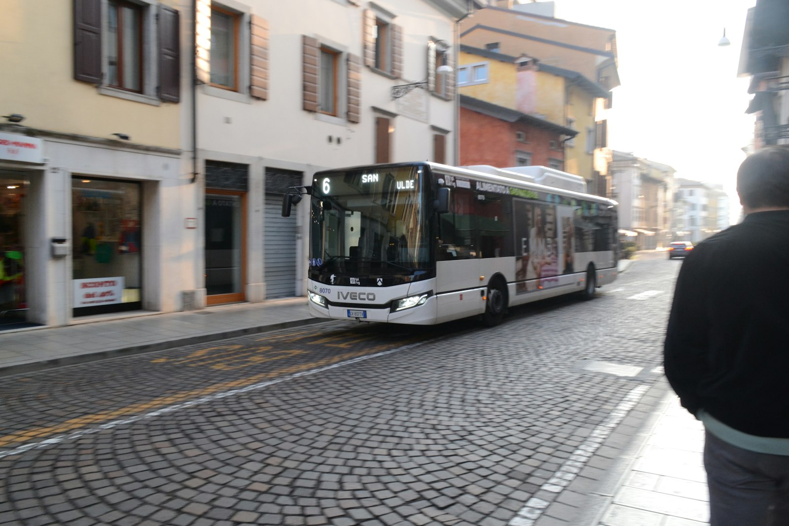 City bus driving along a cobbled street in an Italian town