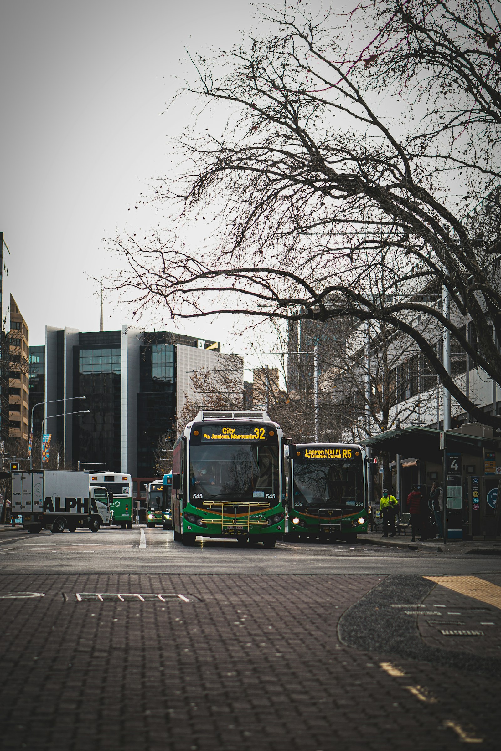 City buses lined up at terminal bays beside a station square