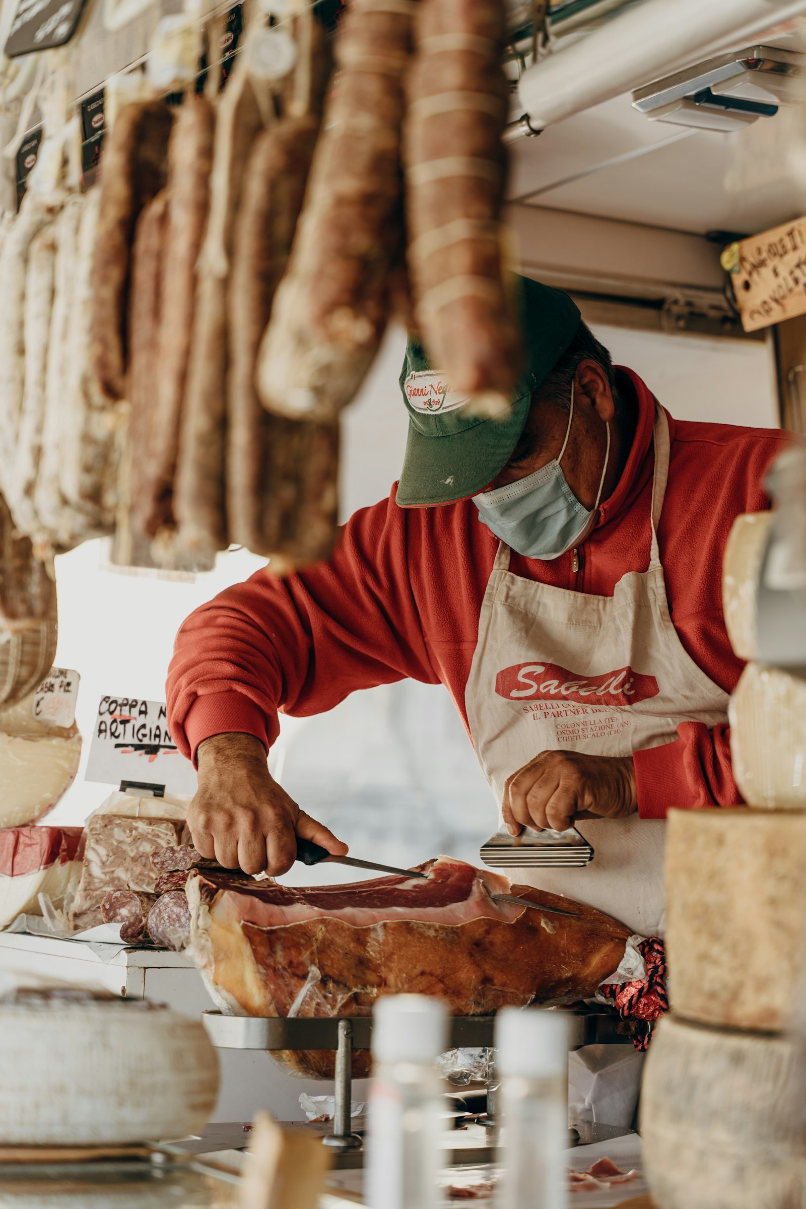 Shop assistant slicing cured meat behind a deli counter