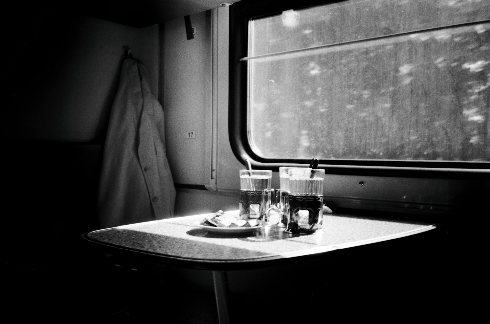 Two drinks resting on a table beside a train window