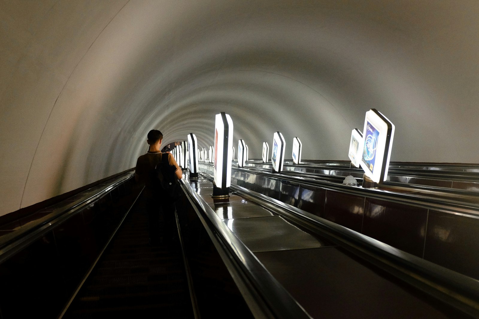 Passenger riding an escalator down towards a metro platform