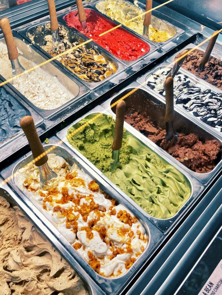 Gelato display case filled with different flavours behind glass