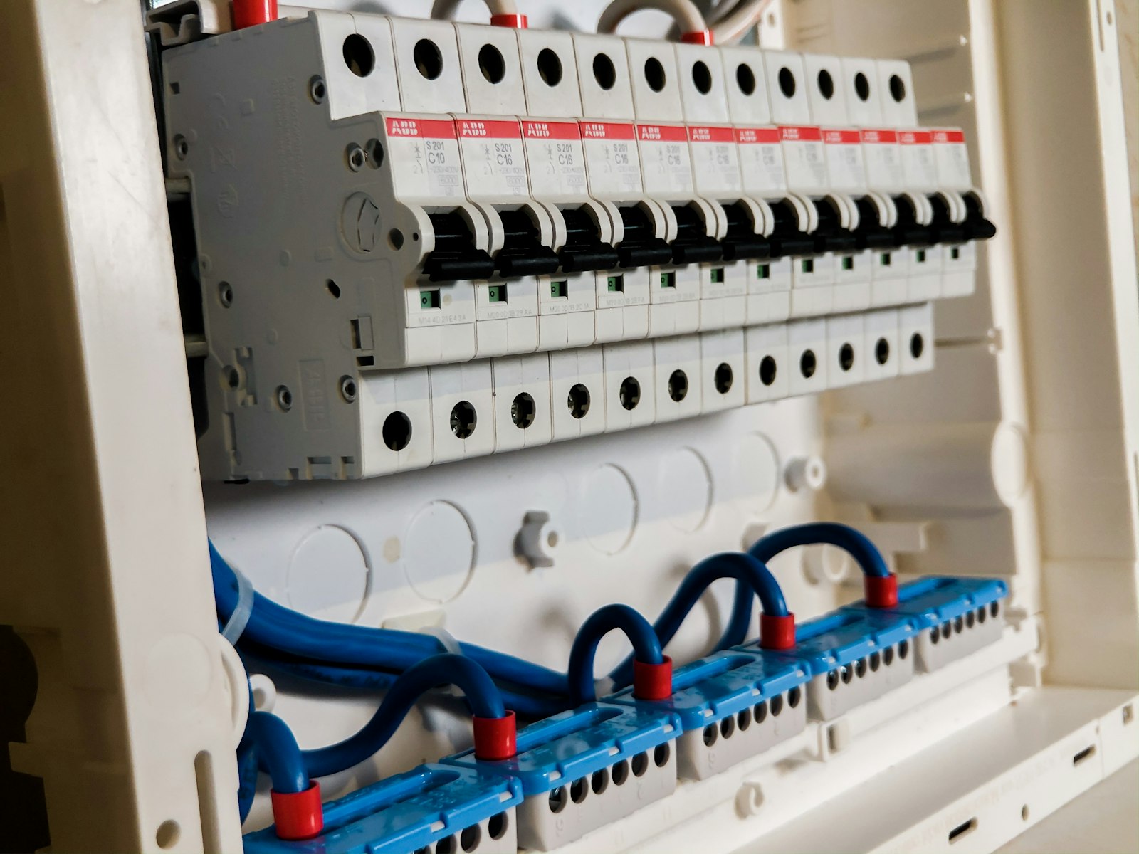 Row of white circuit breakers inside a domestic electrical panel