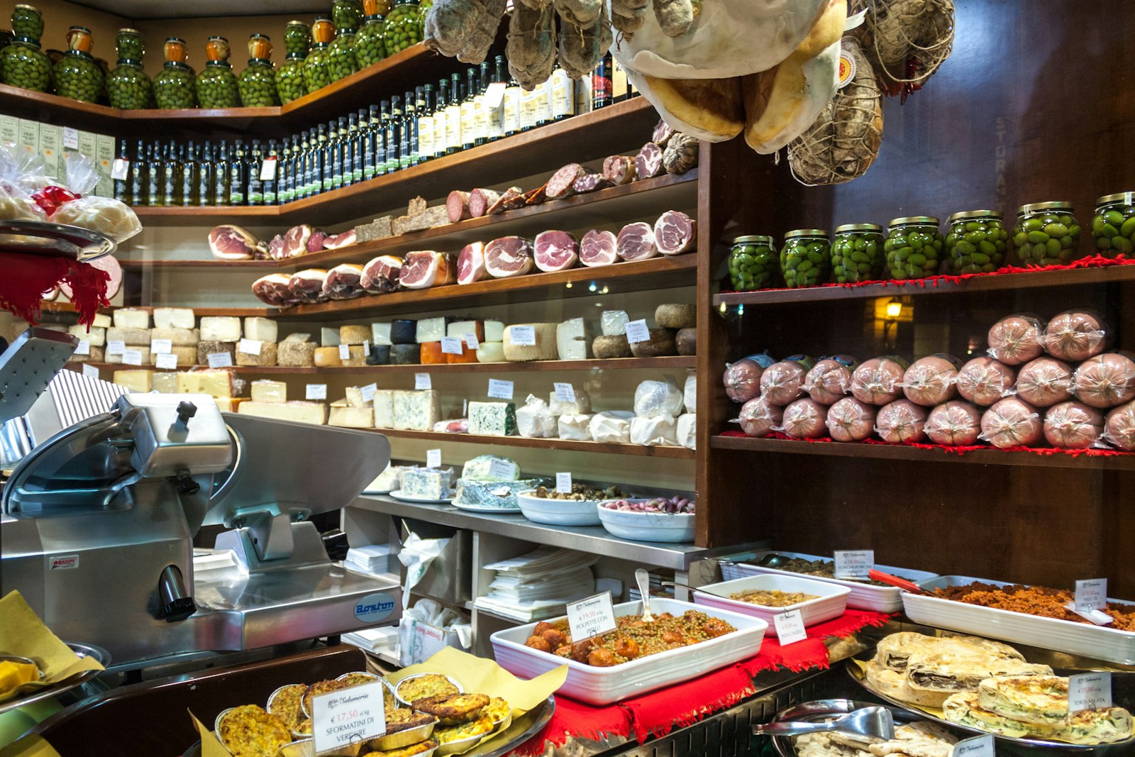 Italian deli counter filled with cheeses and cured meats behind glass