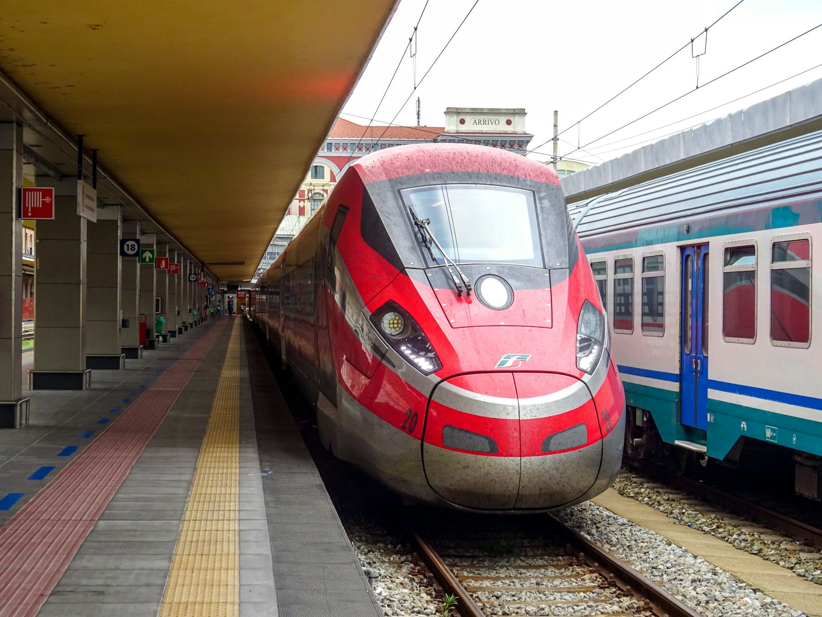Red high-speed train waiting at an Italian station platform