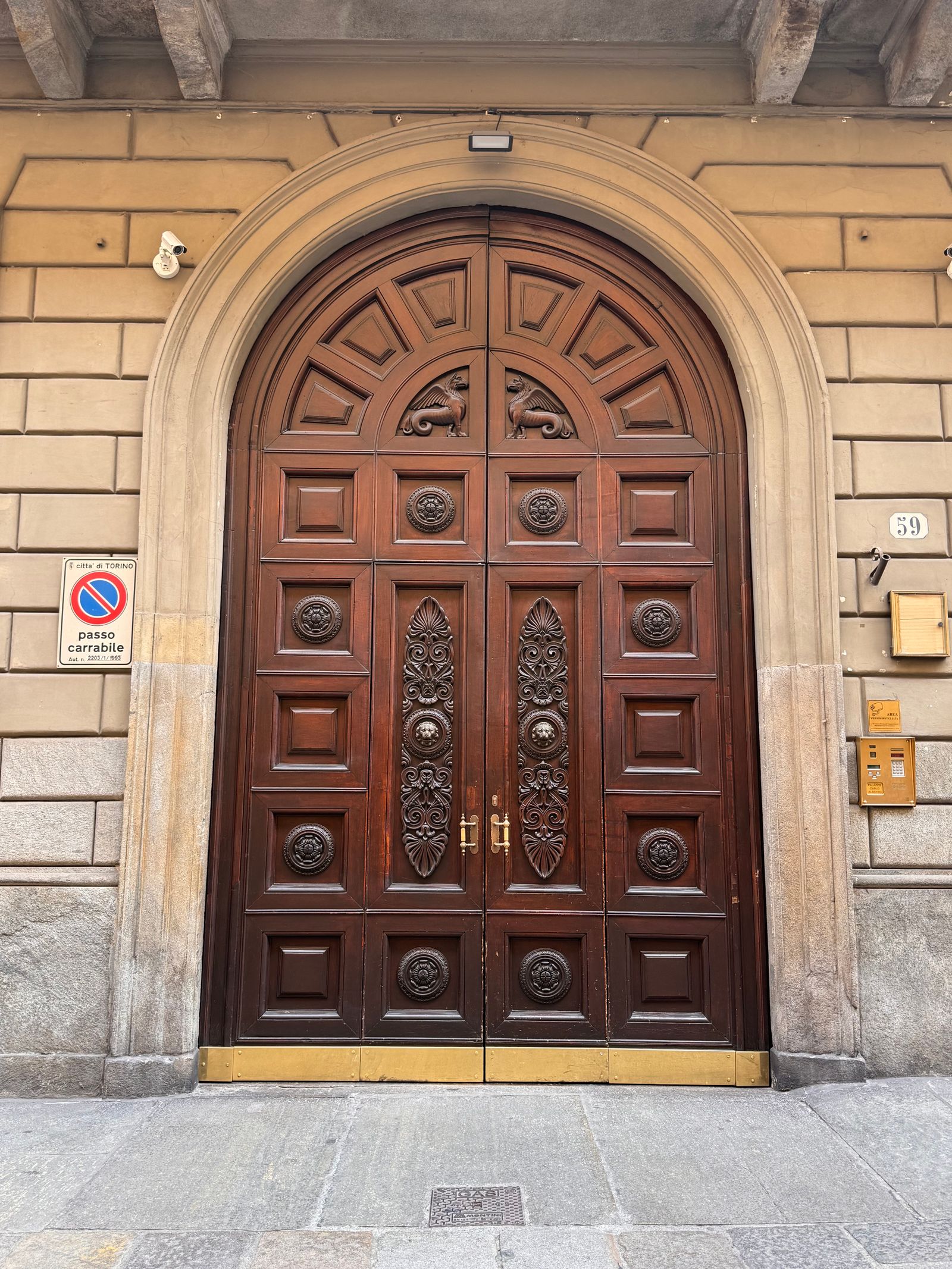 Large ornate wooden entrance door set in an arched stone doorway on a historic building facade