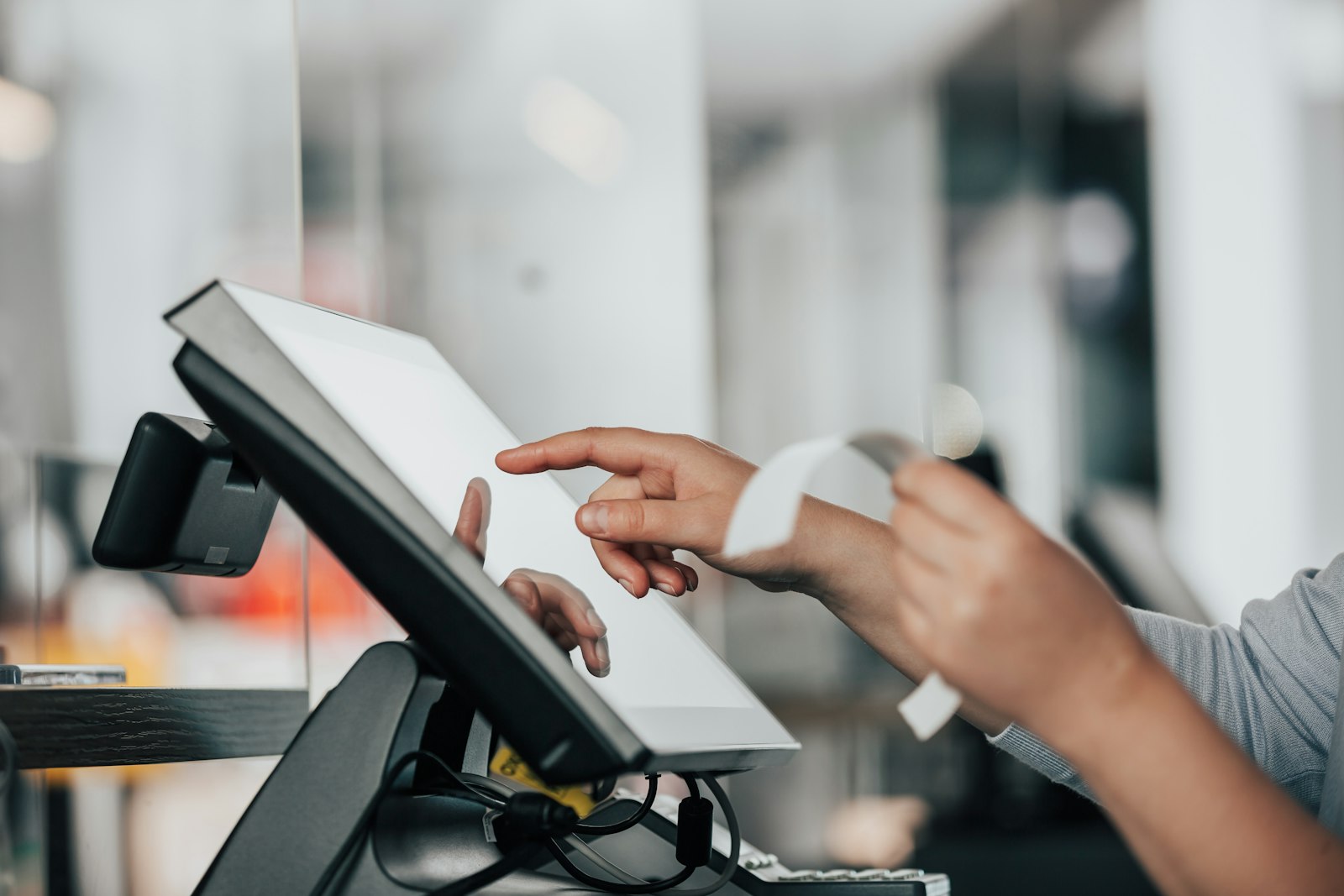 Shop assistant using a card terminal at the counter of a store in Italy