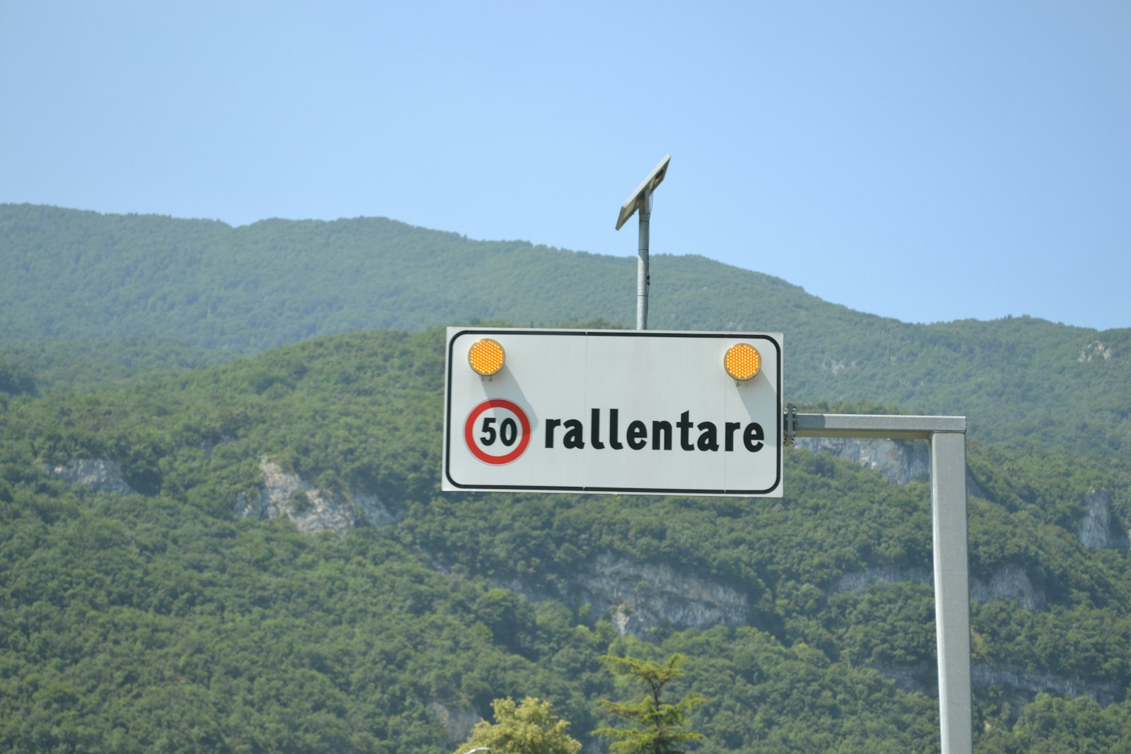Italian road sign telling drivers to slow down to the posted speed limit