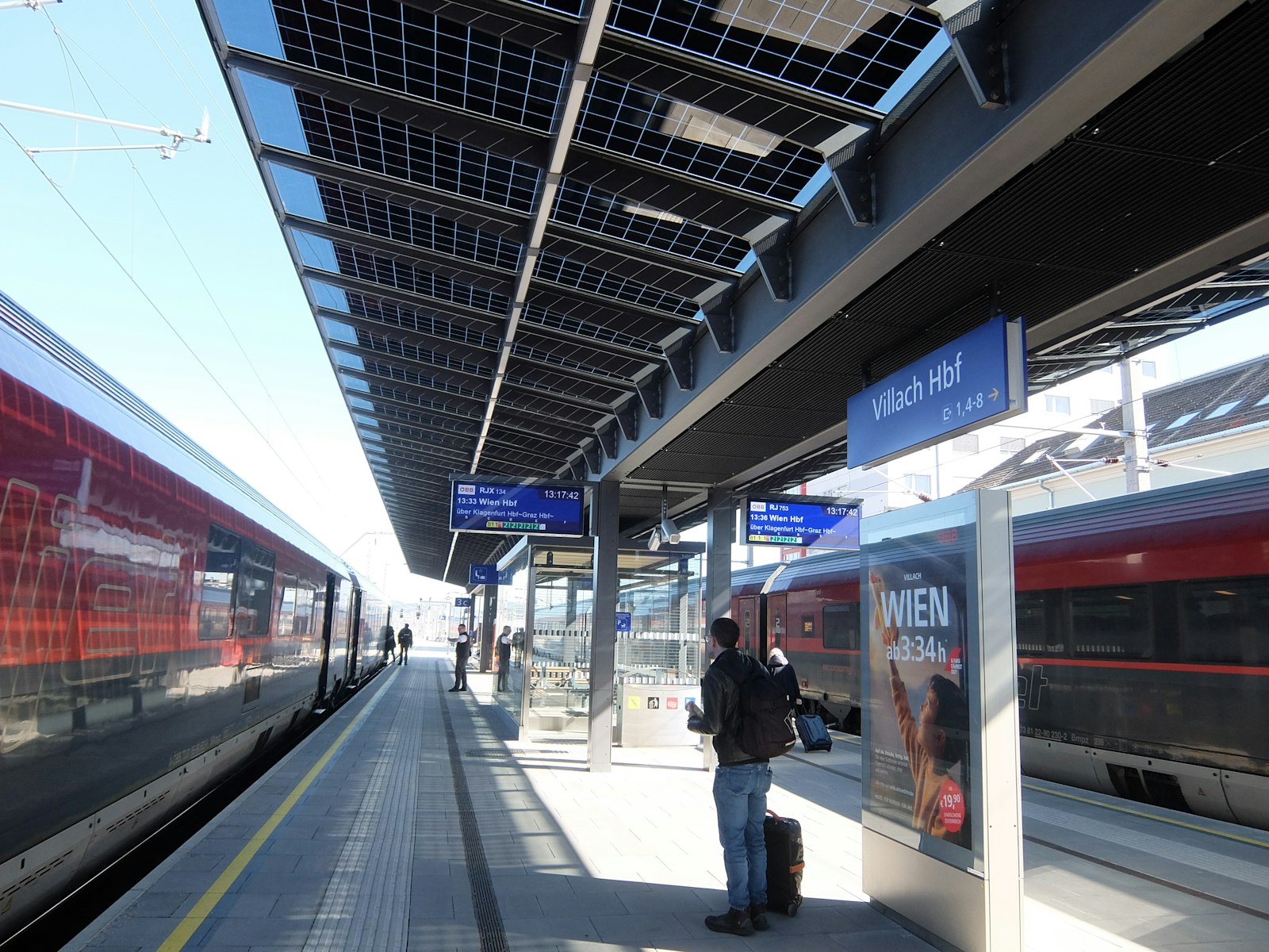 Travellers on a modern train station platform beside waiting trains