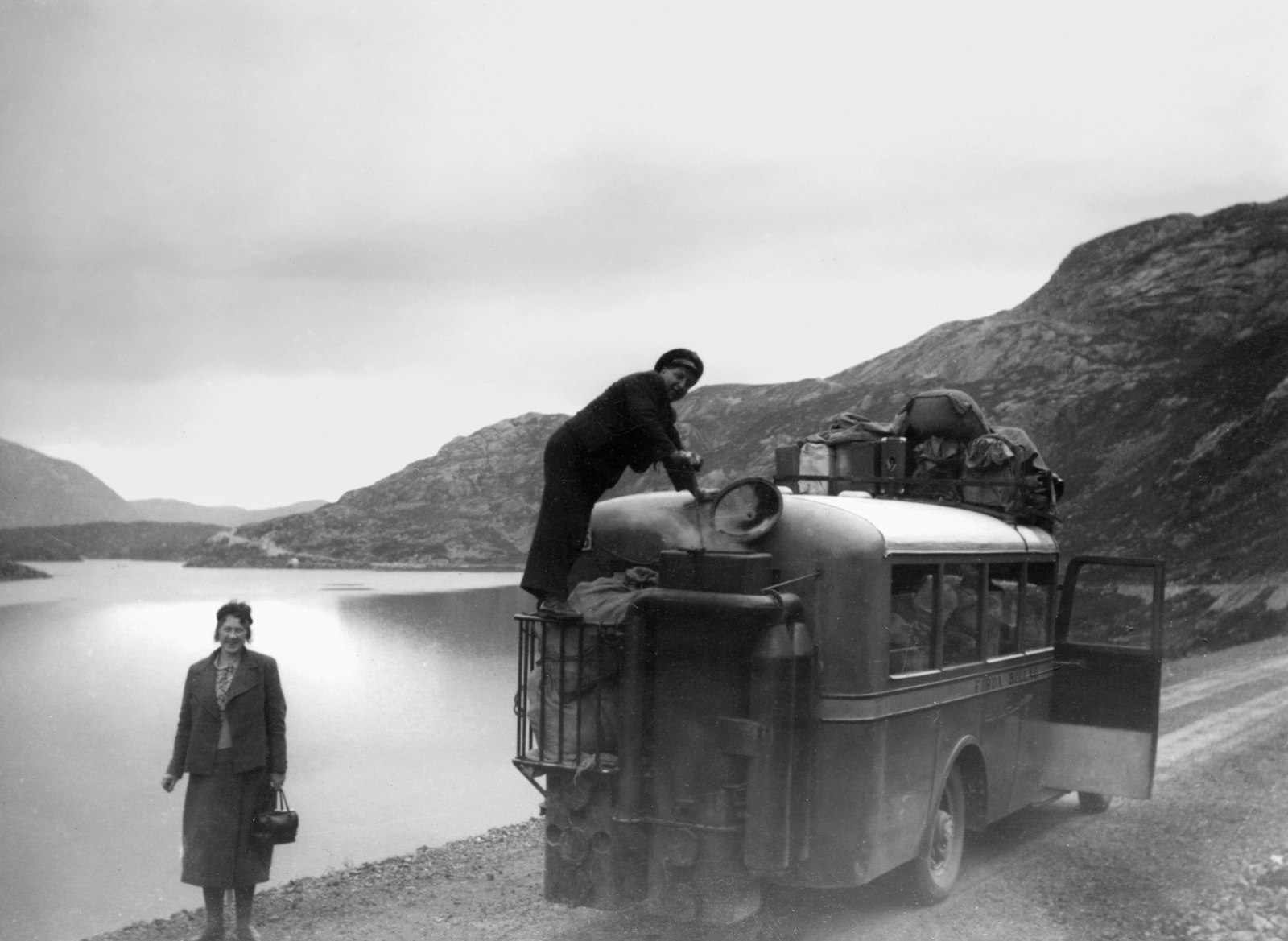 Passengers loading suitcases into the luggage hold of a coach