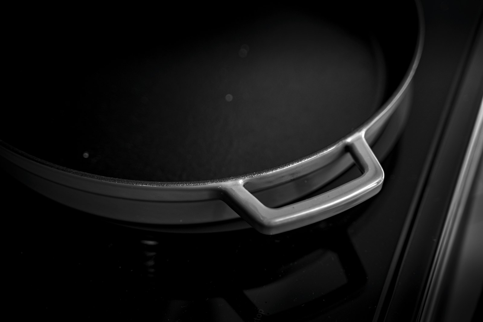 Black pan standing on a flat glass induction cooktop
