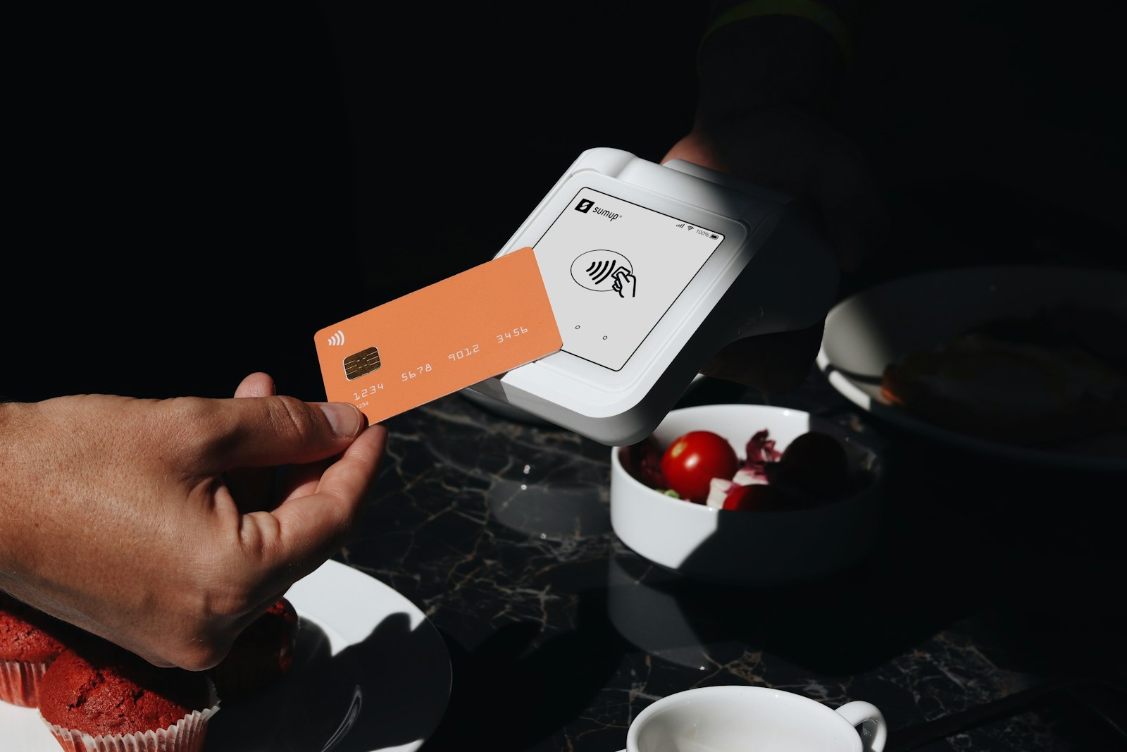 Diner holding a credit card above a plate while paying at an Italian restaurant table