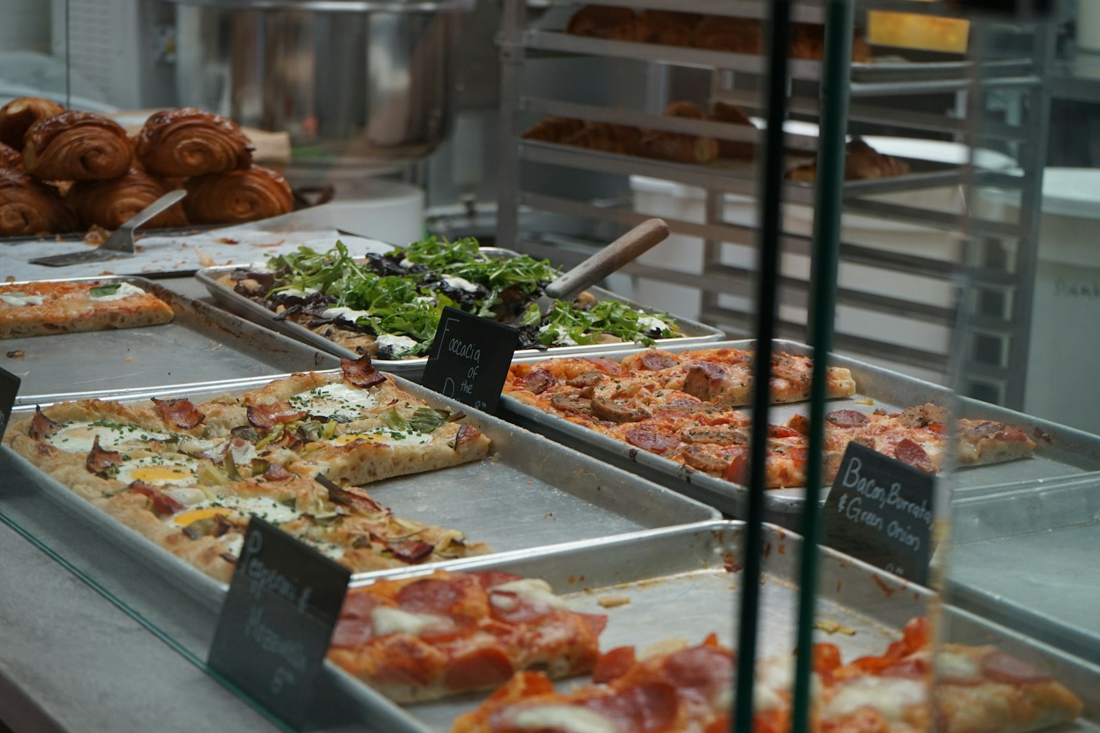 Display case filled with trays of different pizza al taglio varieties