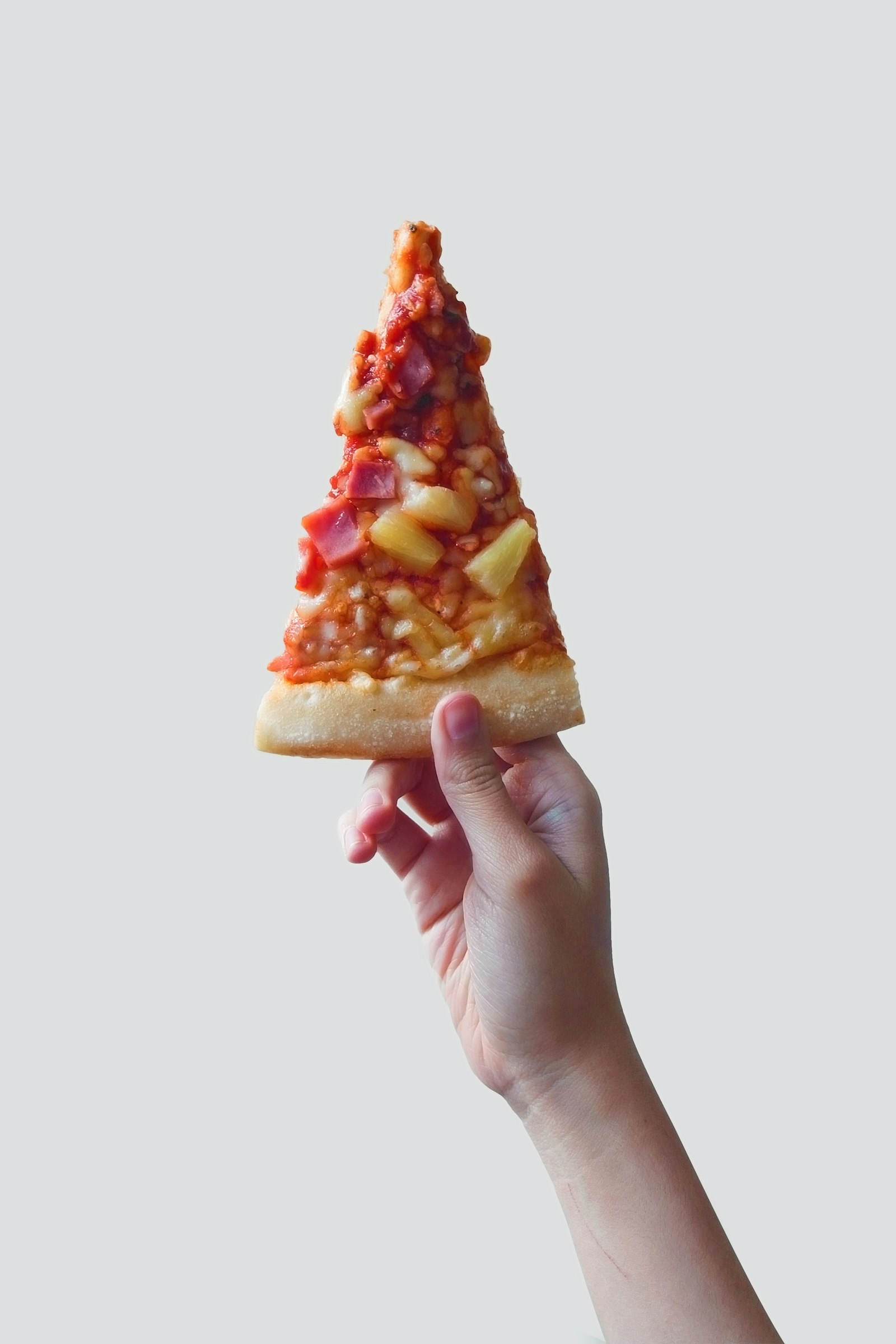 Person holding a folded slice of pizza wrapped in paper