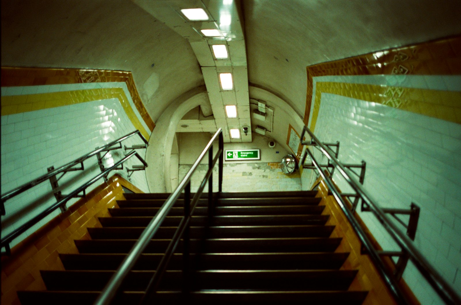 Long tiled station staircase with metal handrails