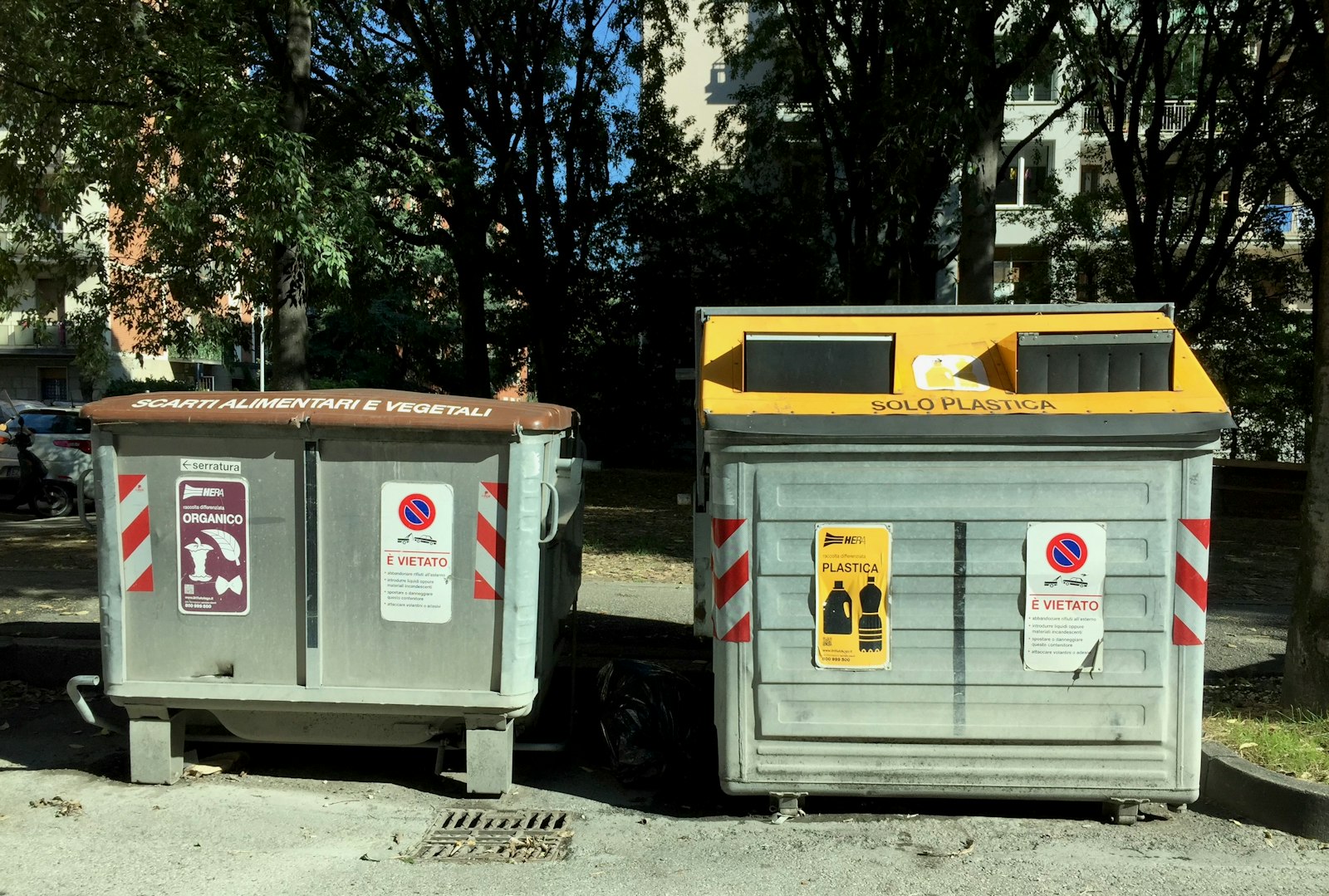 Two street recycling bins at an outdoor waste collection point