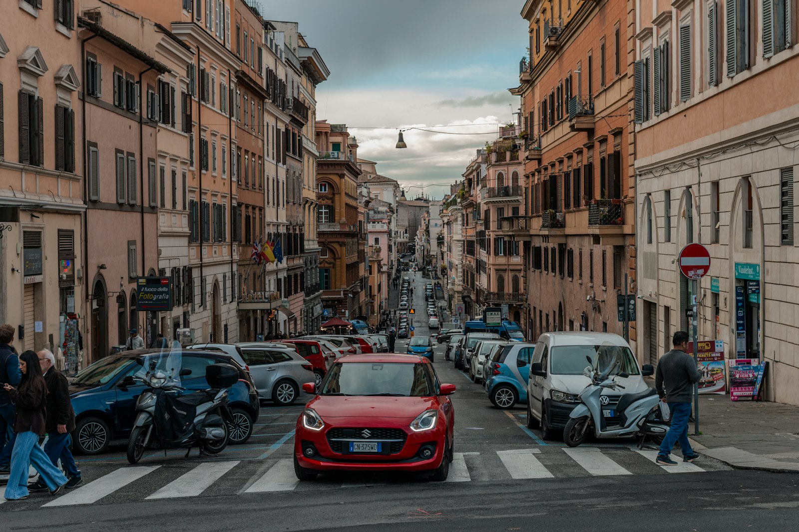 Cars and pedestrians on a street entering an Italian city centre