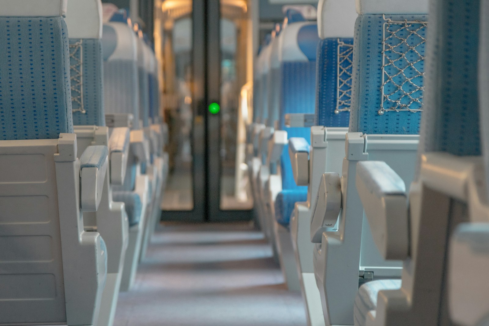 View along the aisle of a train carriage towards the vestibule doors