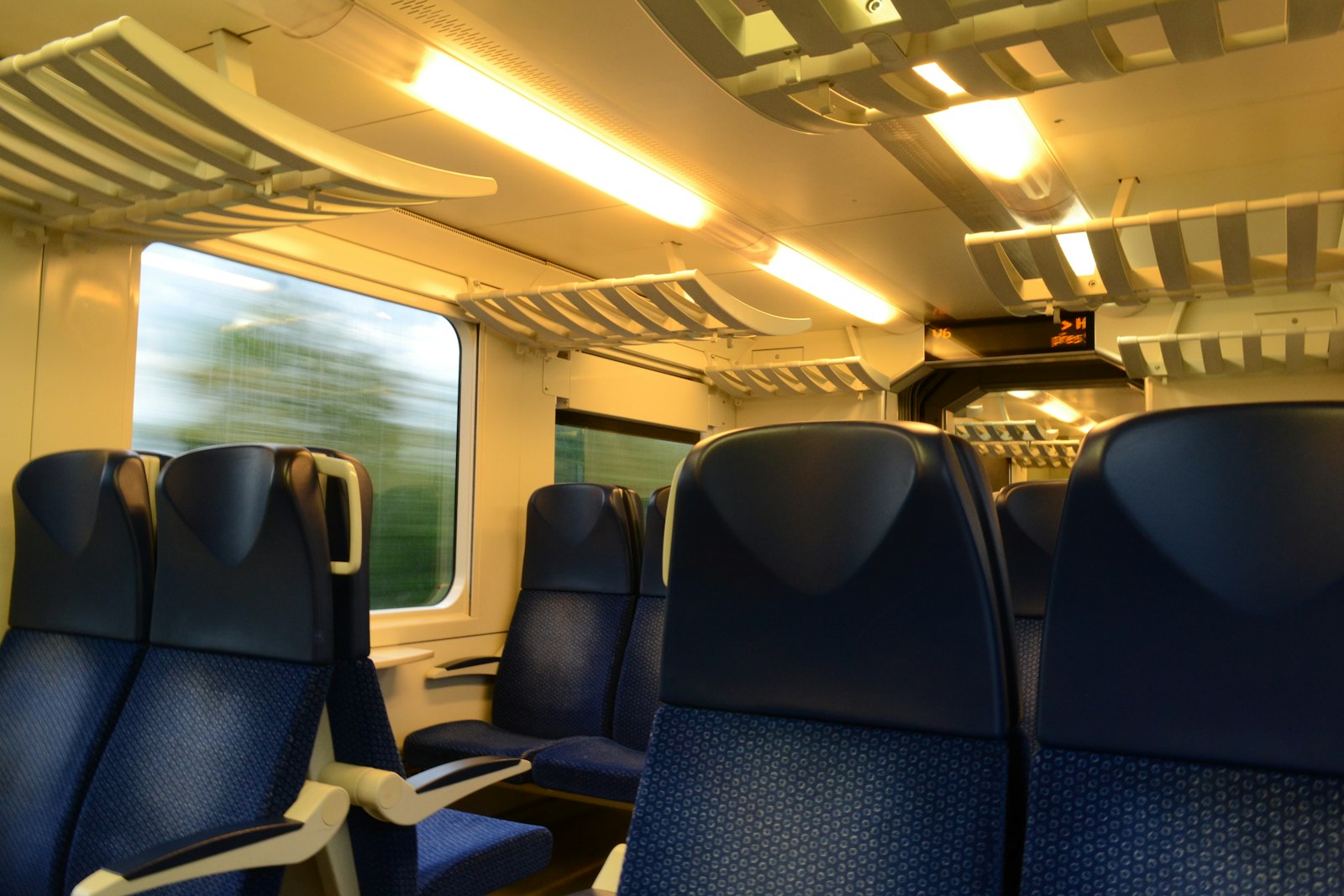 Empty train seats beside a window with passing scenery