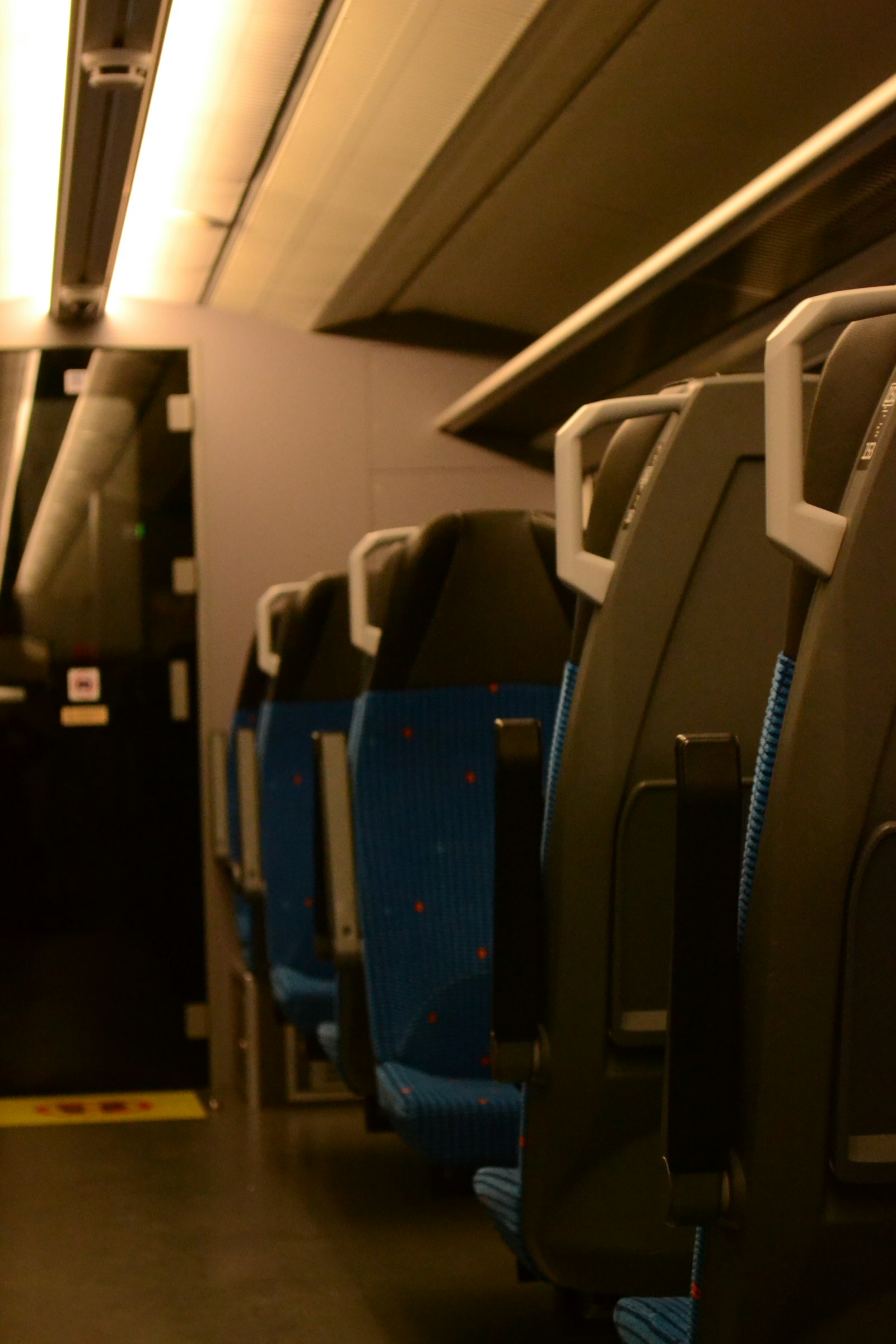 Empty train carriage seats lit by daylight through the windows