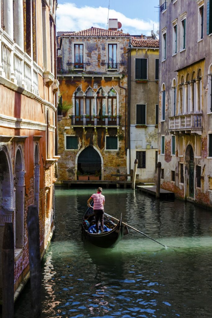 Gondolier rowing a gondola along a narrow canal in Venice