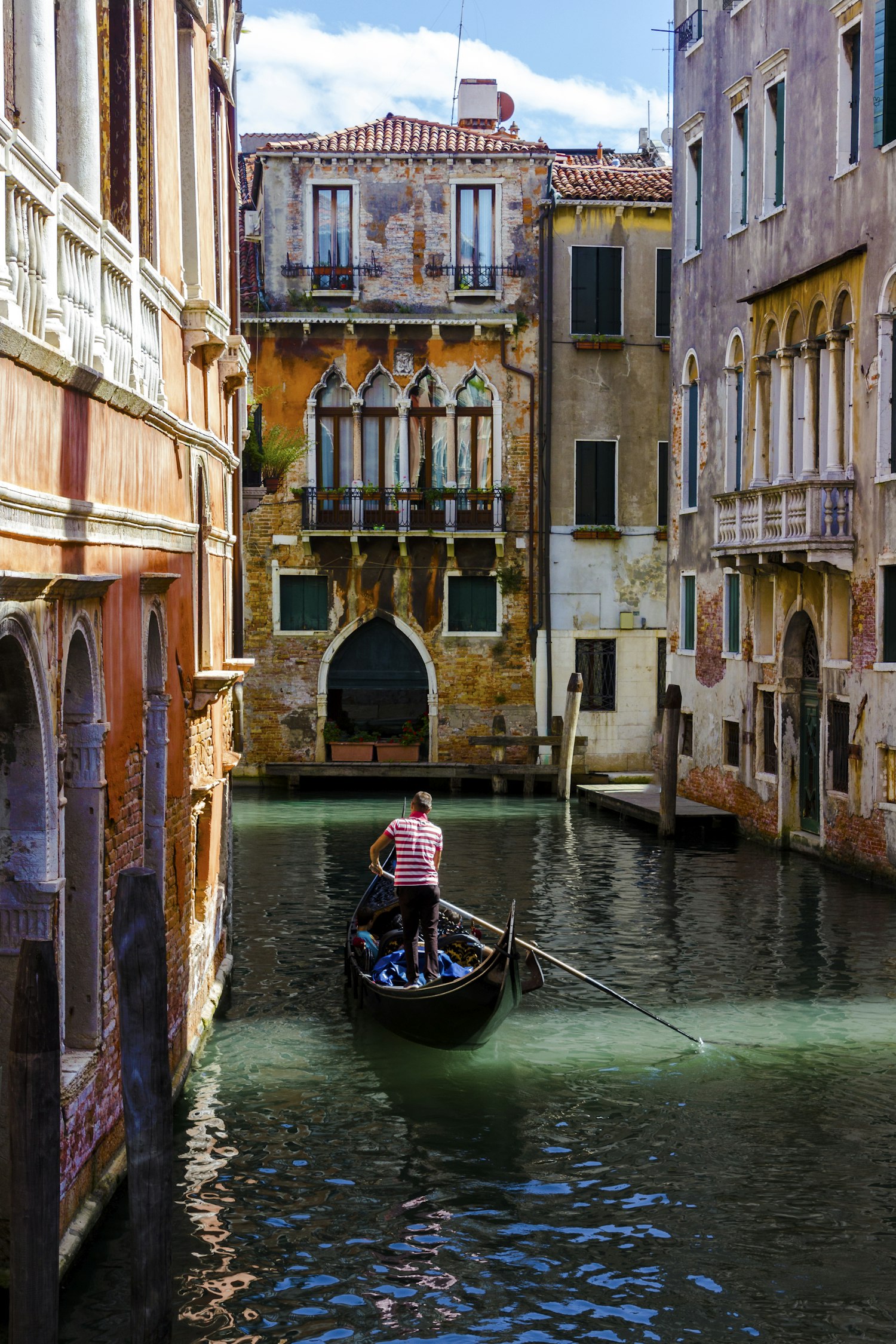 Gondolier rowing a gondola along a canal in Venice