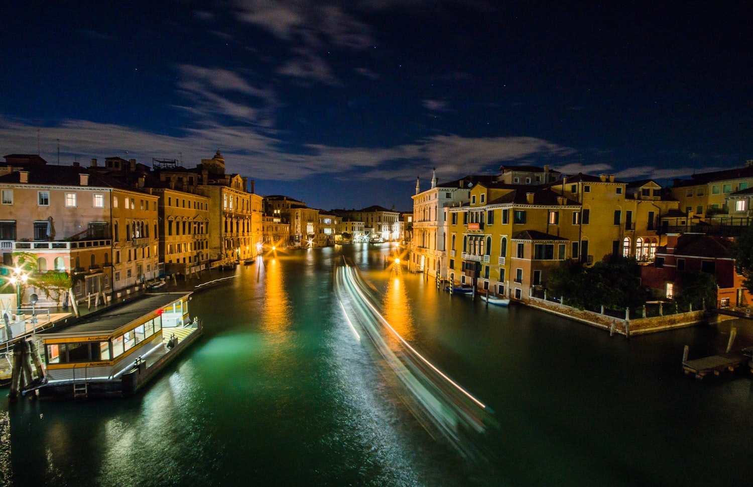 Vaporetto waiting at a lit pier on the Grand Canal in Venice at night