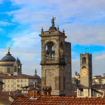 Scenic view of historic towers in Bergamo, Italy, under a vibrant blue sky.